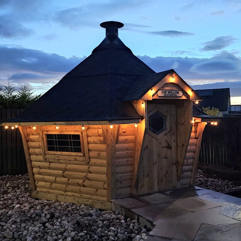 Night time exterior shot of a BBQ cabin with festoon lights