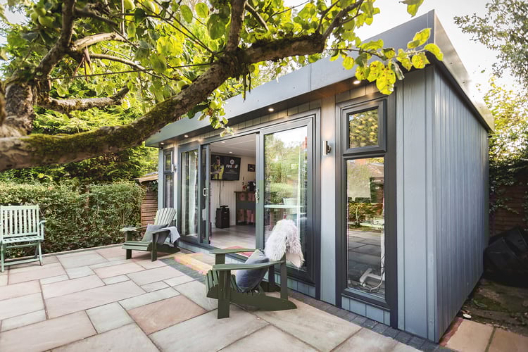 Zero maintenance garden room with open sliding doors and outdoor furniture on patio outside