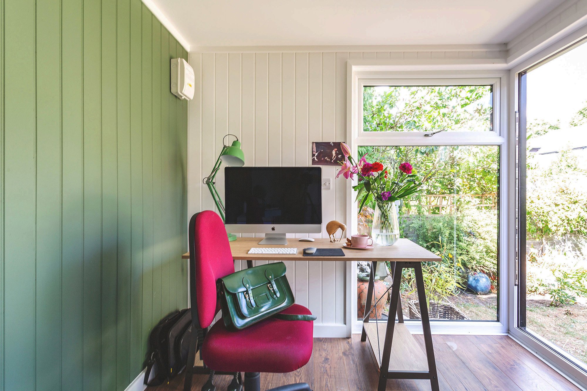 Interior of a small garden office with wifi, desk, chair and lamp