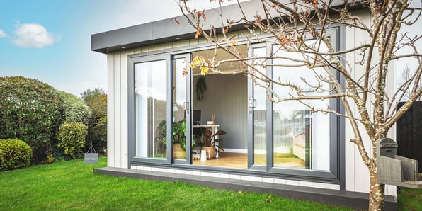 Zero maintenance garden office with black sliding doors open so you can see desk