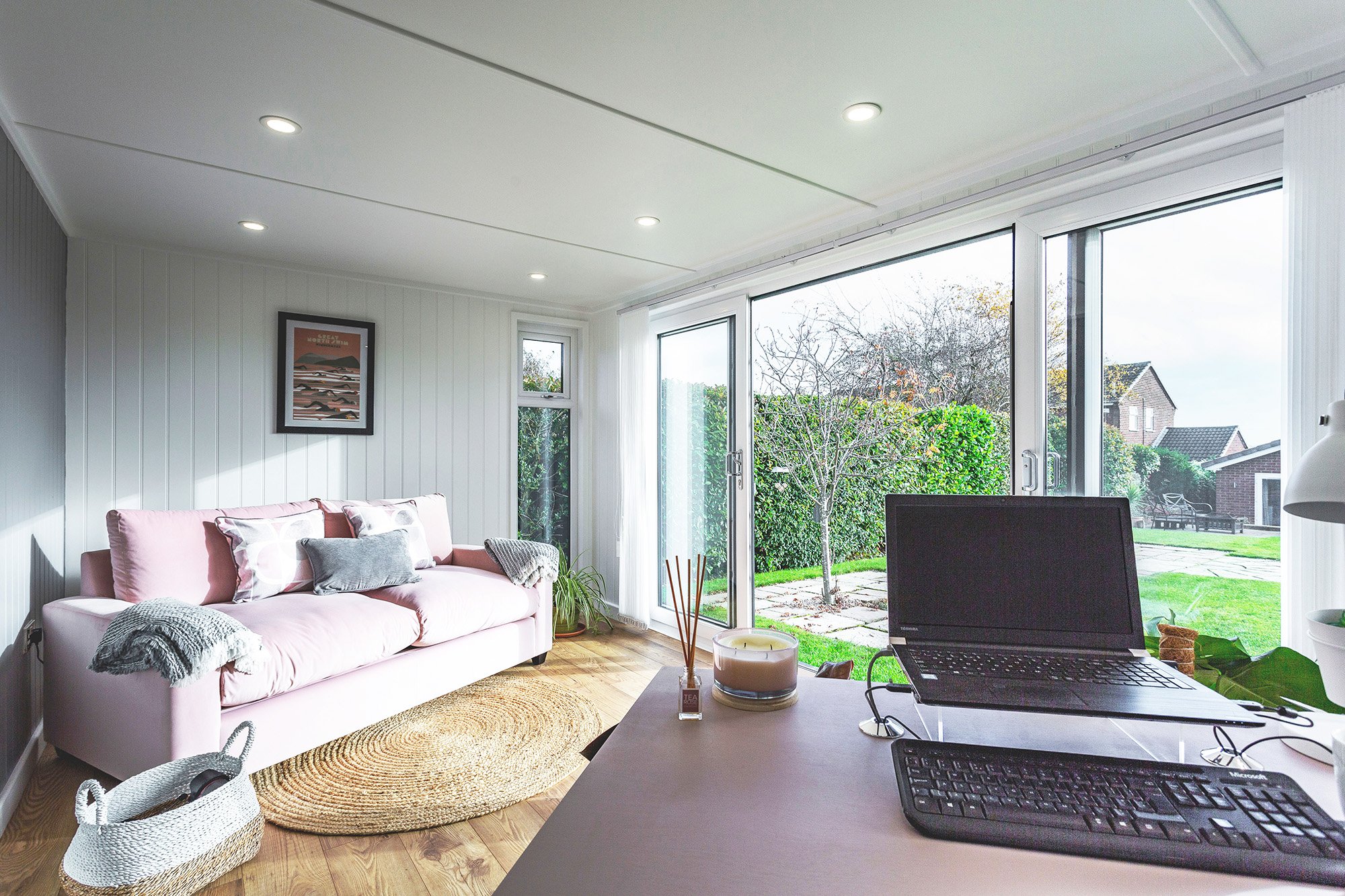 Inside a Garden Office with desk, laptop and pink velvet sofa