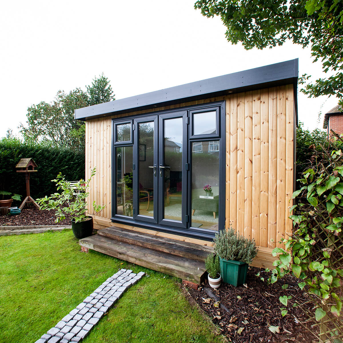 redwood garden pod timber building in lawn area with patio walkway
