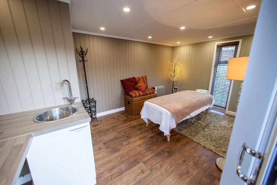 inside view of redwood garden room with massage table and home furnishings with sink unit
