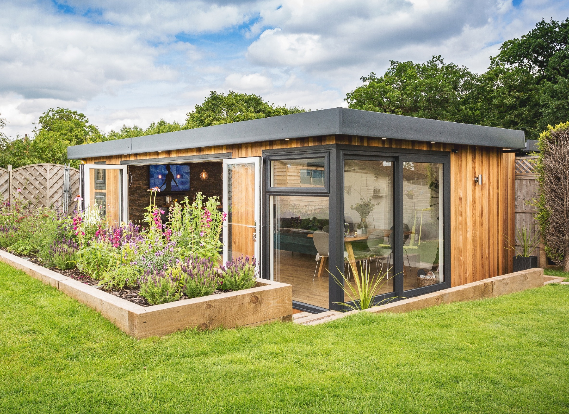 Large insulated garden bar with open bifold doors, set behind raised planters