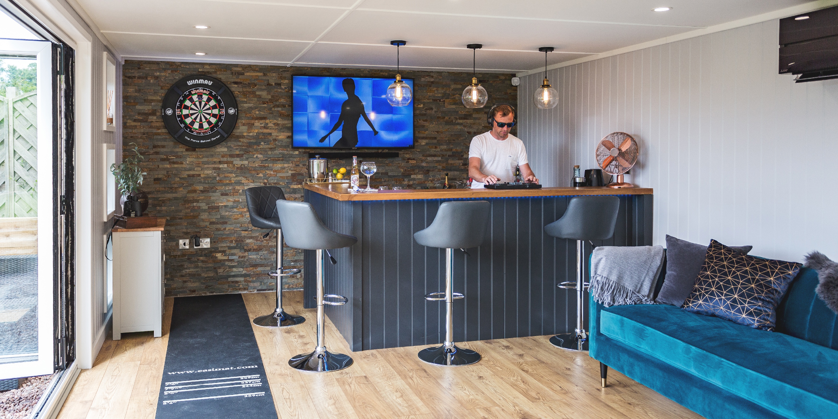 Interior of a garden bar man cave with man behind bar area DJing