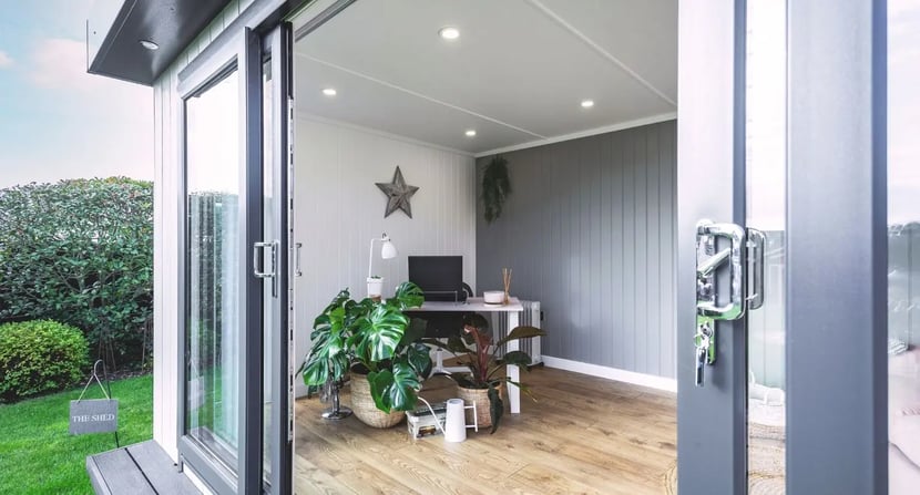 Bright and minimal garden office with desk, indoor plants, and wooden flooring—ideal as a stylish and quiet revision space for older children and teens during exam time.