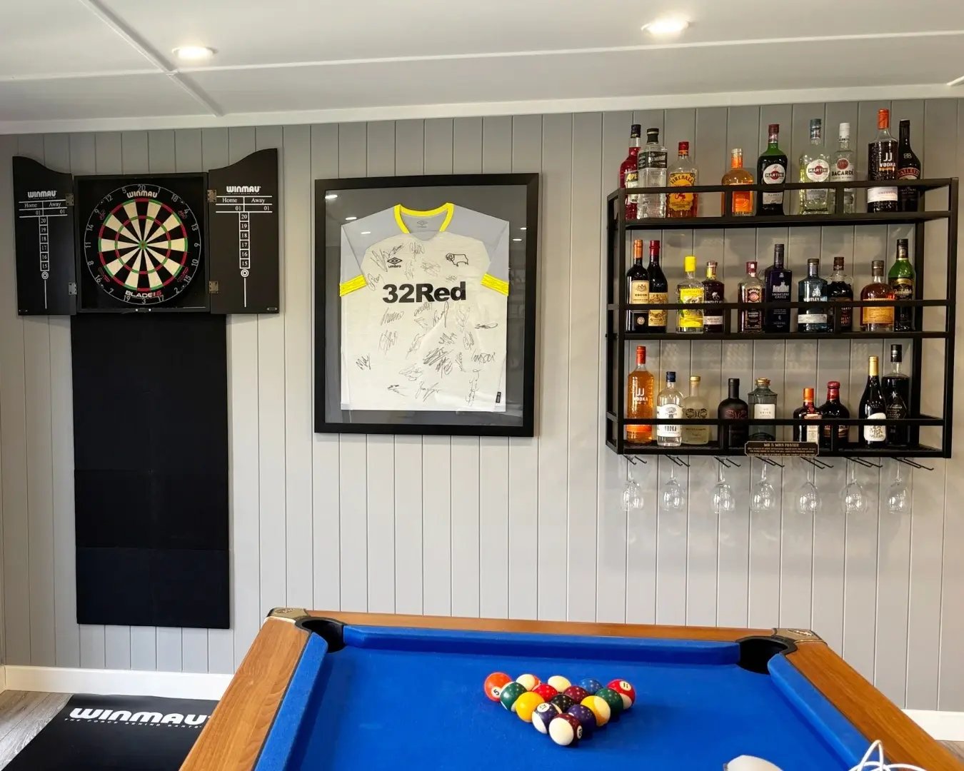 Modern garden entertainment room with pool table, TV area and bespoke home bar.