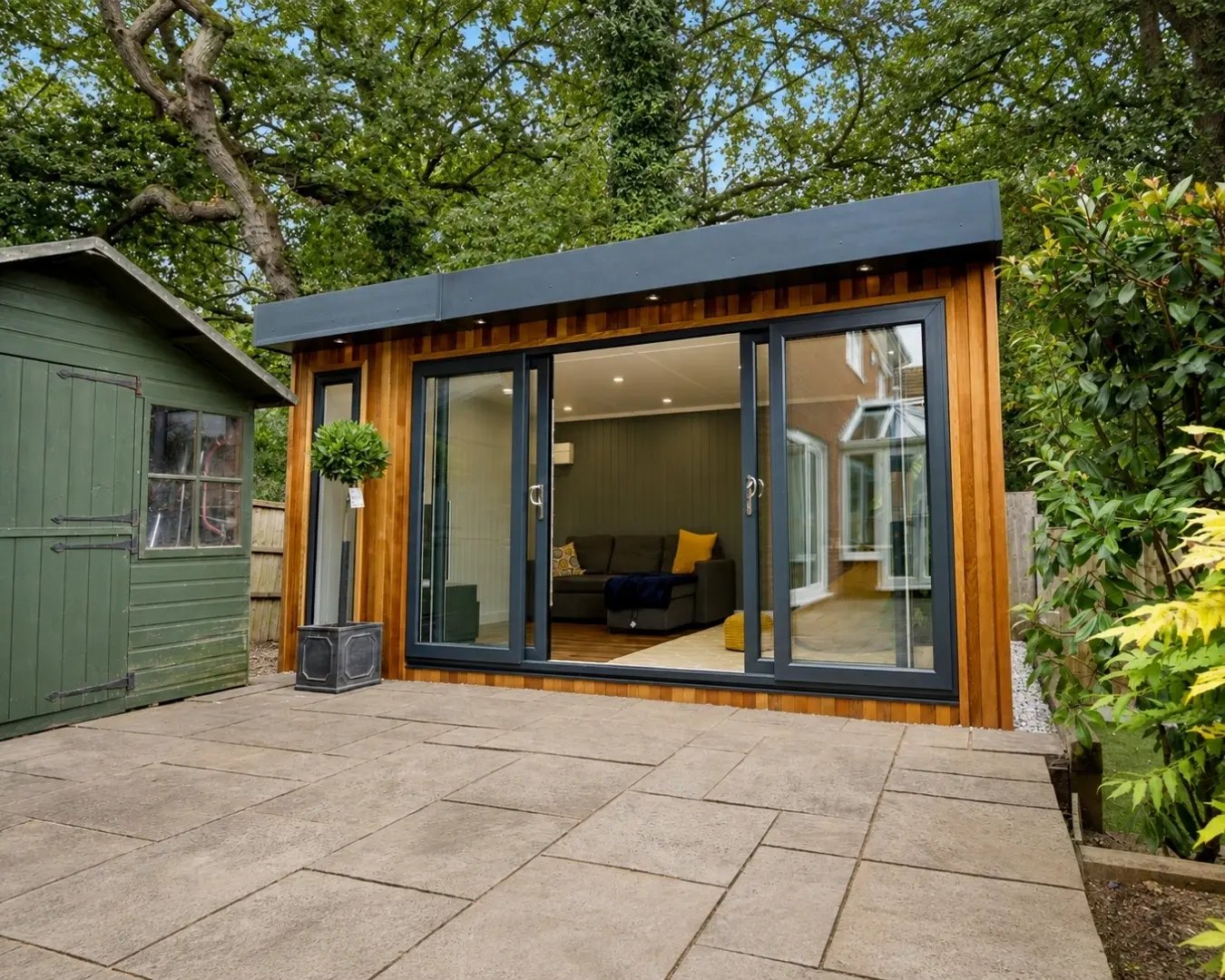 Modern cedar-clad garden room with anthracite bifold doors overlooking the patio.