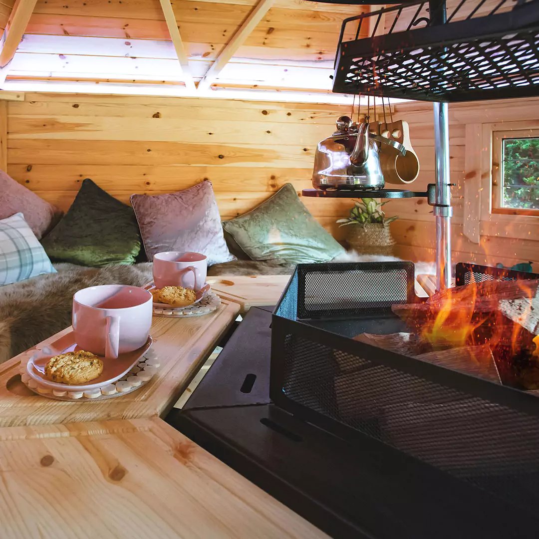 Internal shot of a BBQ hut with fire lit and a cup of tea on tray table
