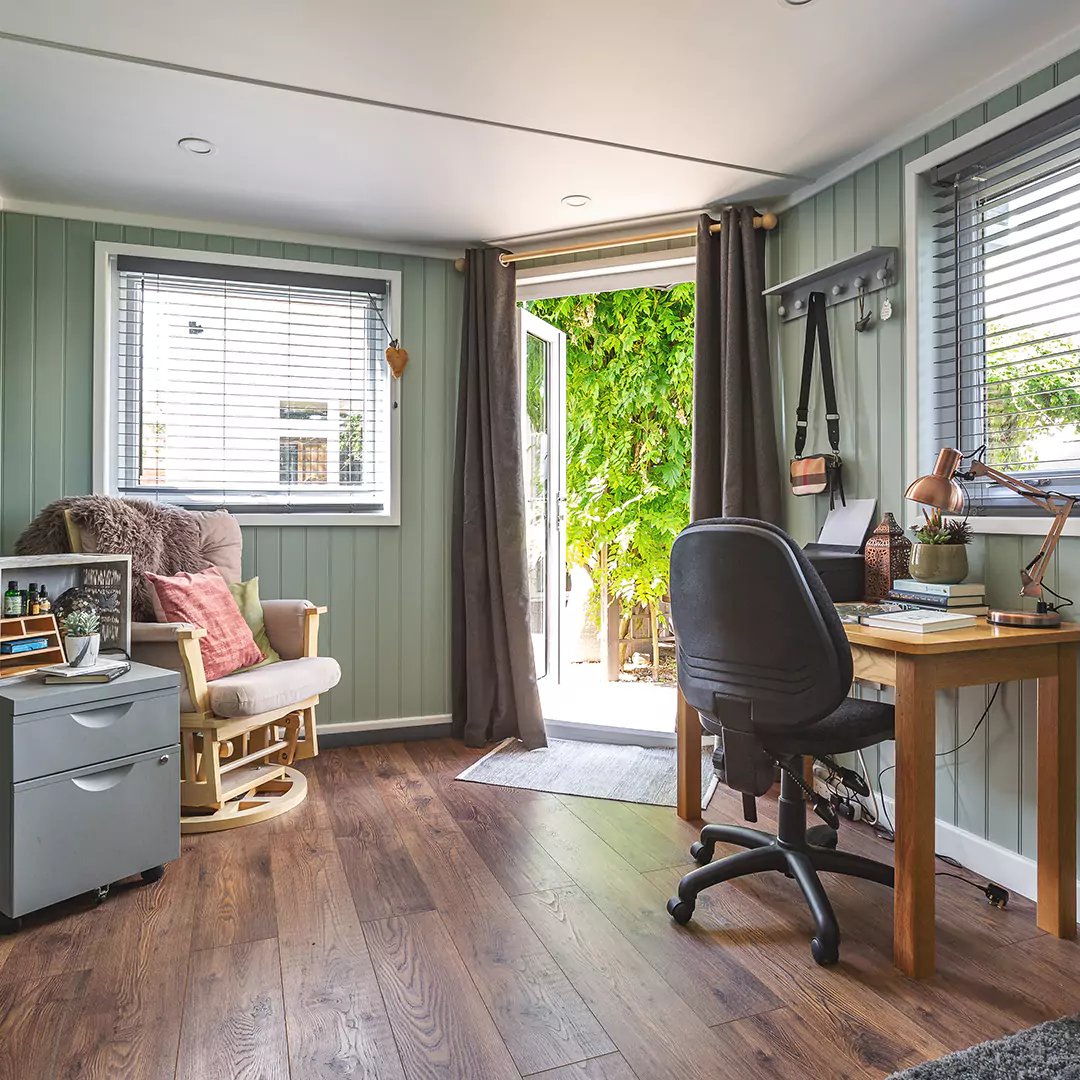 Internal shot of a chic, relaxed home garden office with desk and comfy seating