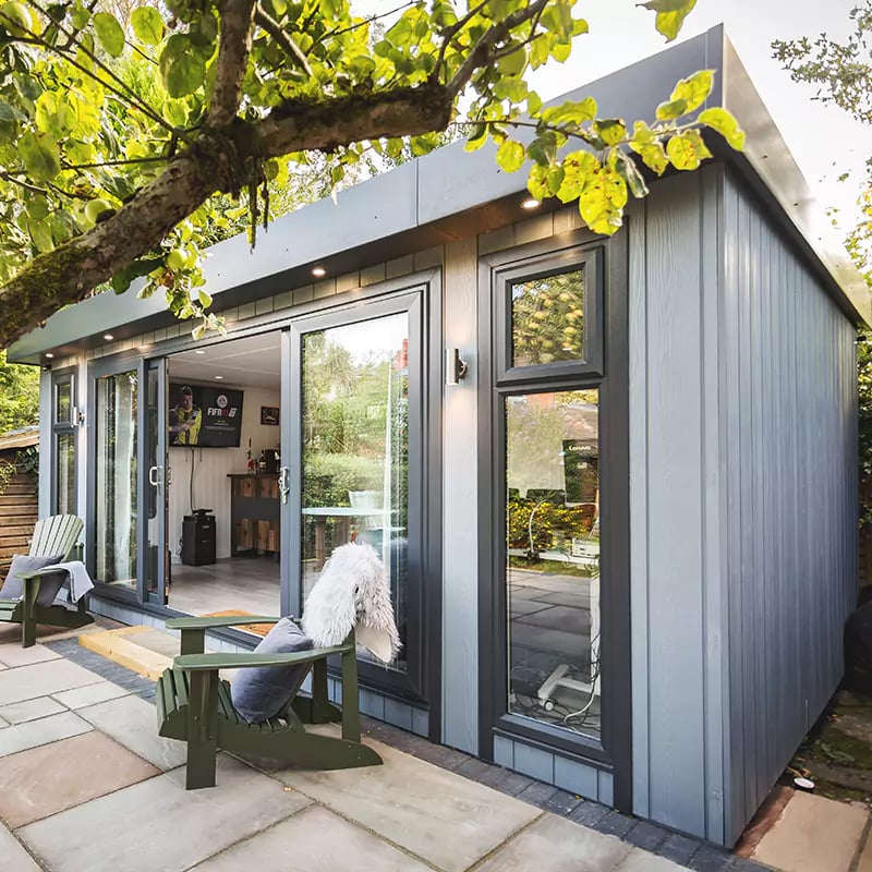 External shot of a zero maintenance garden room in light grey cladding with blush pink velvet sofa