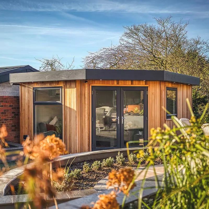 Small corner room garden office in redwood, with black doors and windows
