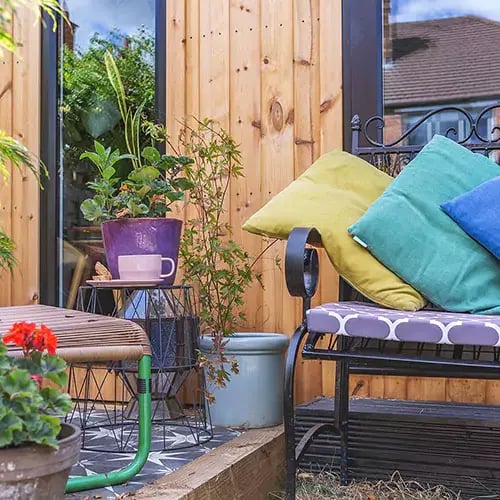 garden office building with bench outside and green patent leather satchel with view of vase with flowers