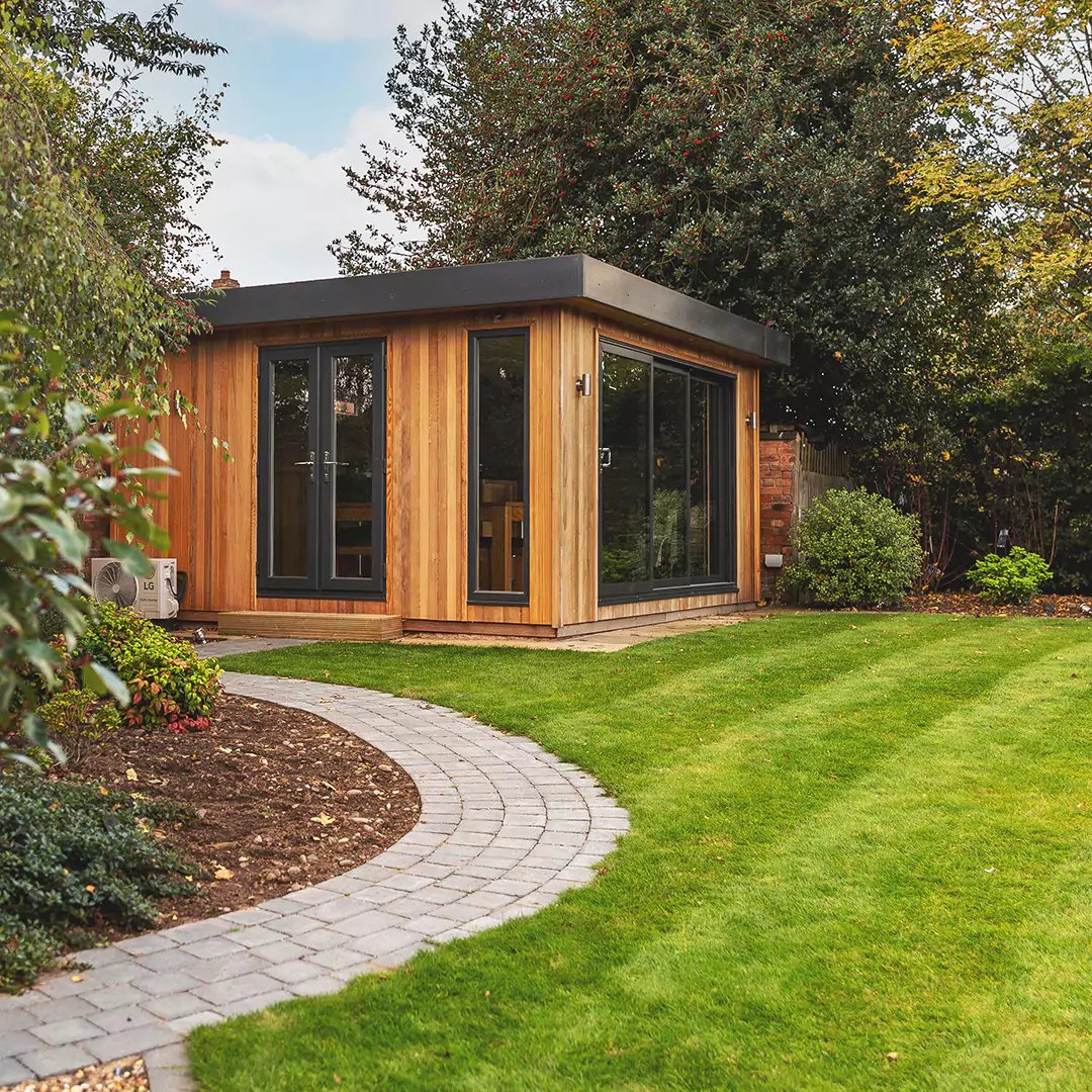 a timber man cave garden building with sliding glass doors and pool table and bar area inside