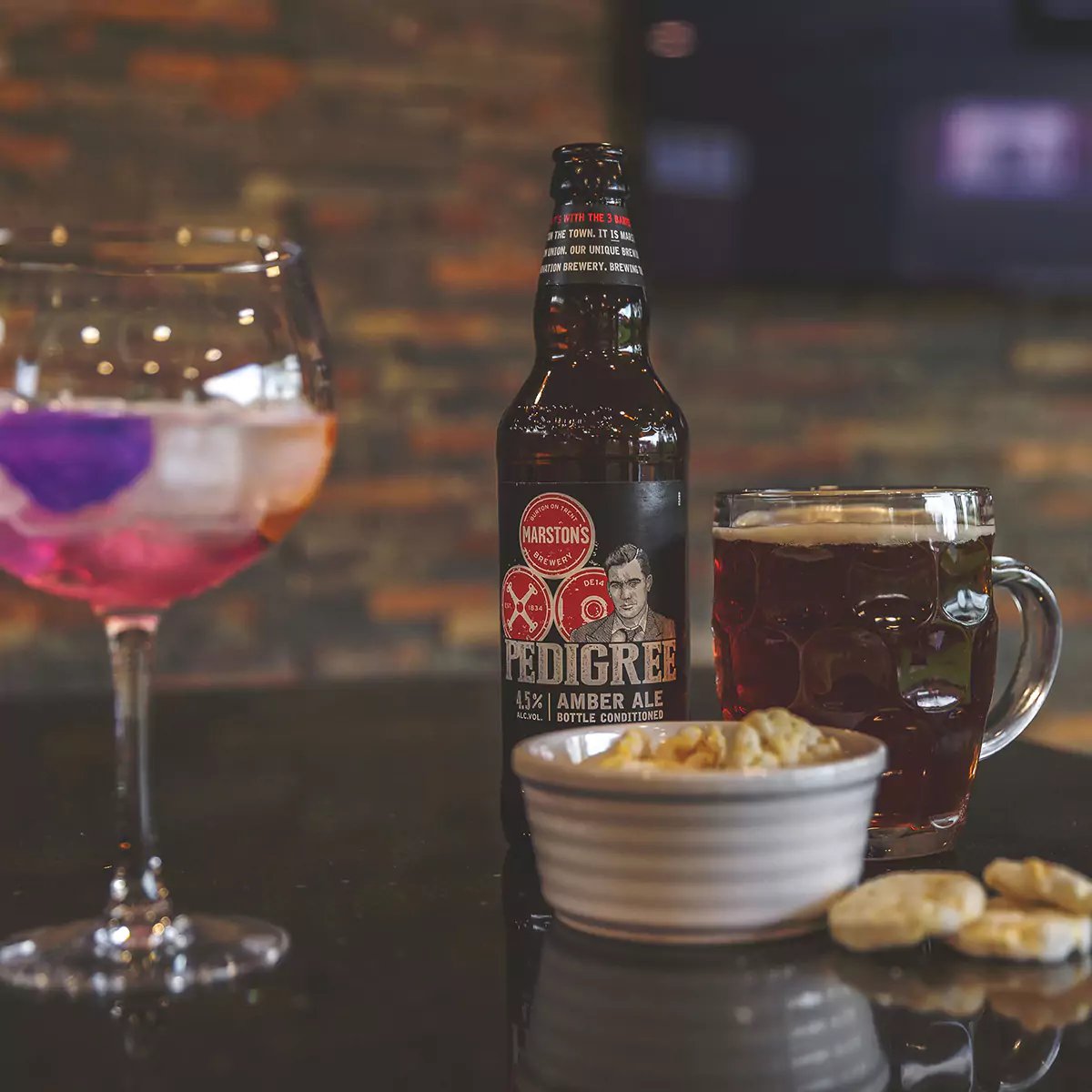 large garden man cave with bar with glass of gin, a pint of pedigree amber ale and bowl of crisps 