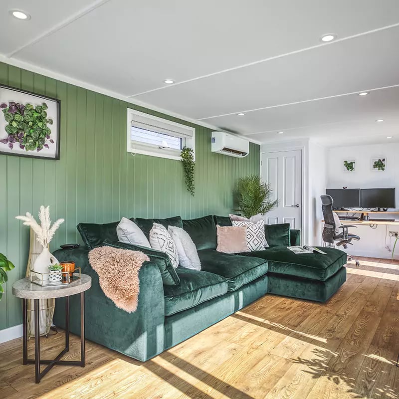 Interior of a small garden office with bottle green velvet sofa & soft furnishings