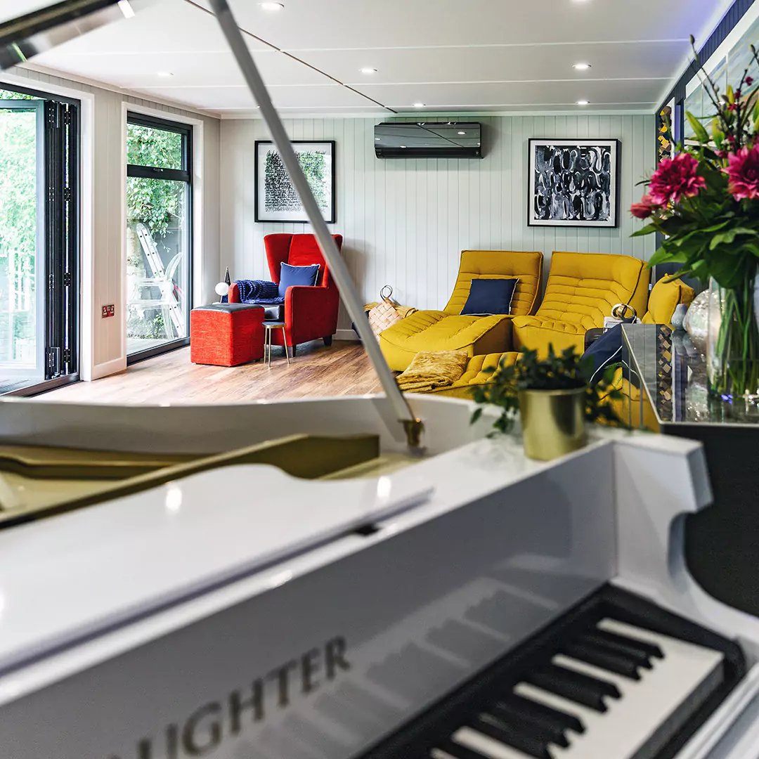 Interior of a garden studio with bright seating and piano