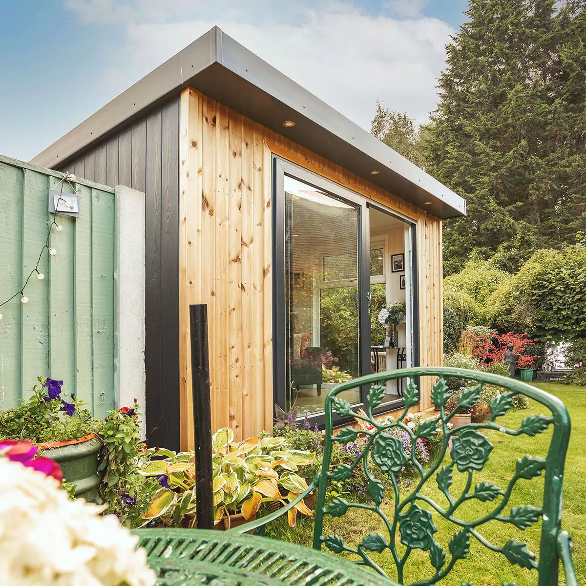 small garden summerhouse in outdoor area with potted plants and outdoor furniture with chair and tables 