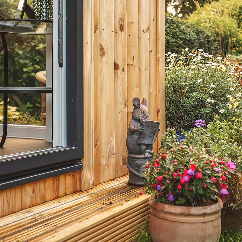 small garden summerhouse in outdoor area with potted plants and outdoor furniture with chair and tables 