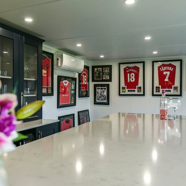 man cave with framed football shirts on wall