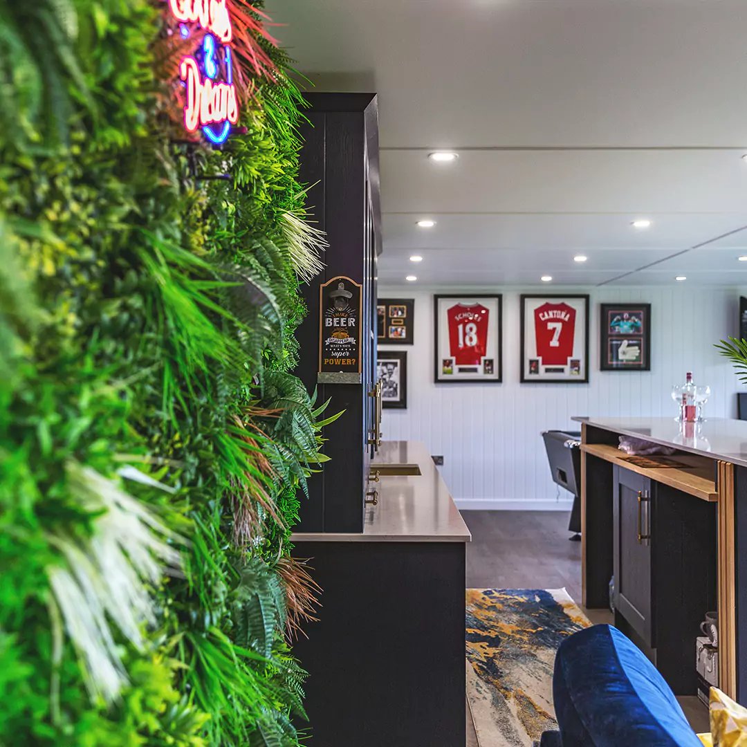 garden man cave interior with plant wall, neon light & framed football shirts hanging on the wall