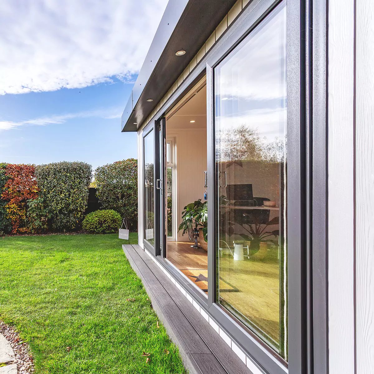 garden office space in lawn area with sliding glass doors surrounded by hedges