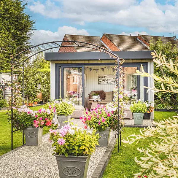 small grey garden summerhouse with decking and rattan furniture with sliding doors open