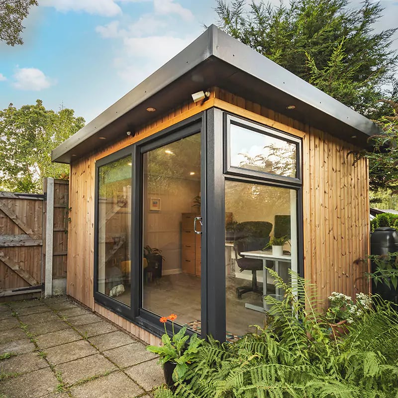 Redwood garden office building with hedge and patio area with view inside office 