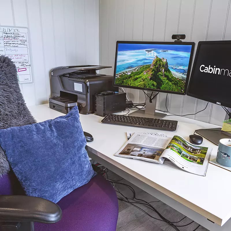 inside view with desk chair and chest of drawers and large white desk with indoor plants and purple sofa cushion