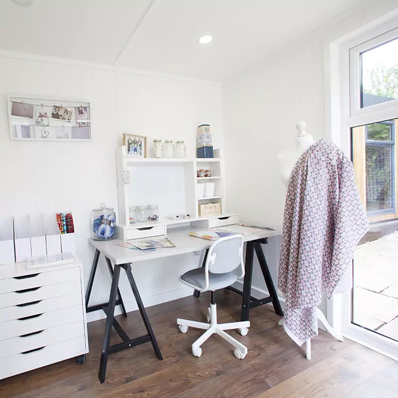 large white desk with blue armchair and notebook on table