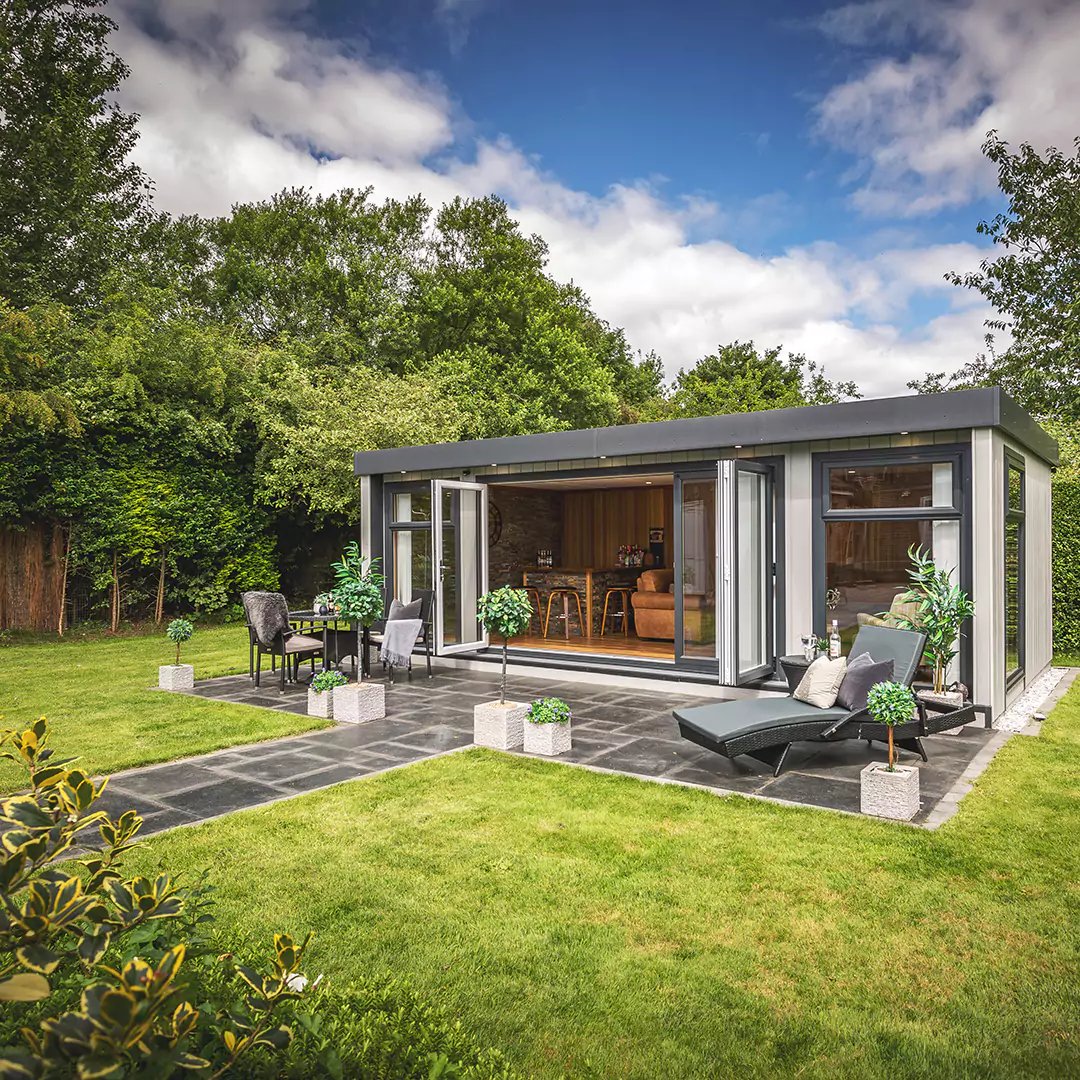 External shot of beautiful large bar shed in garden with open bifold doors and patio area with path