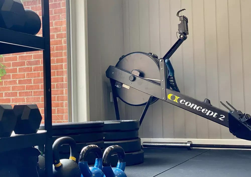 rowing machine and weights on floor in garden gym