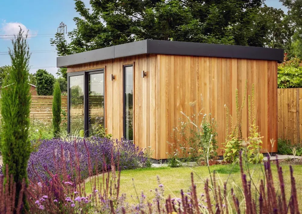 Small insulated timber outdoor gym building with black sliding doors