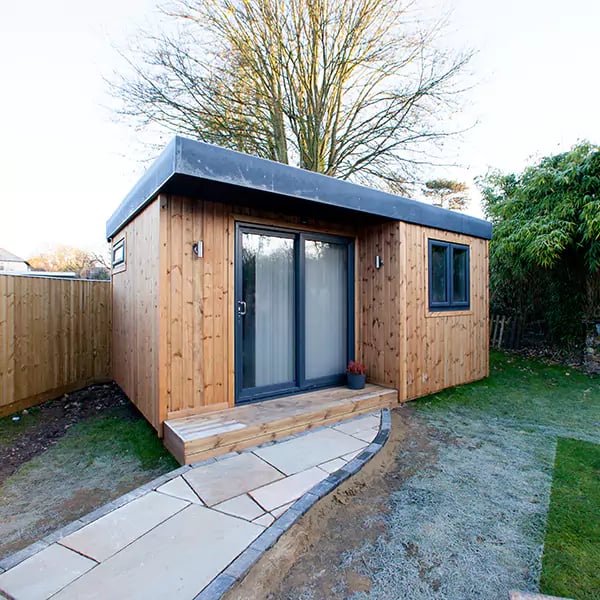 redwood garden massage room with open door and view into building with orange cushions