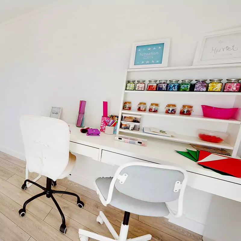 large white desk with blue armchair and notebook on table