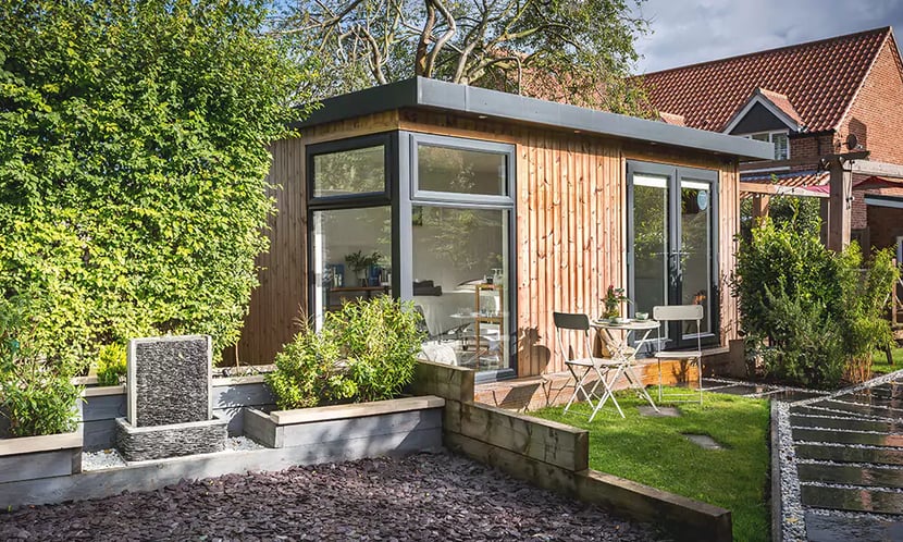 Insulated timber garden room with black french doors and nice neat pathway leading up to room