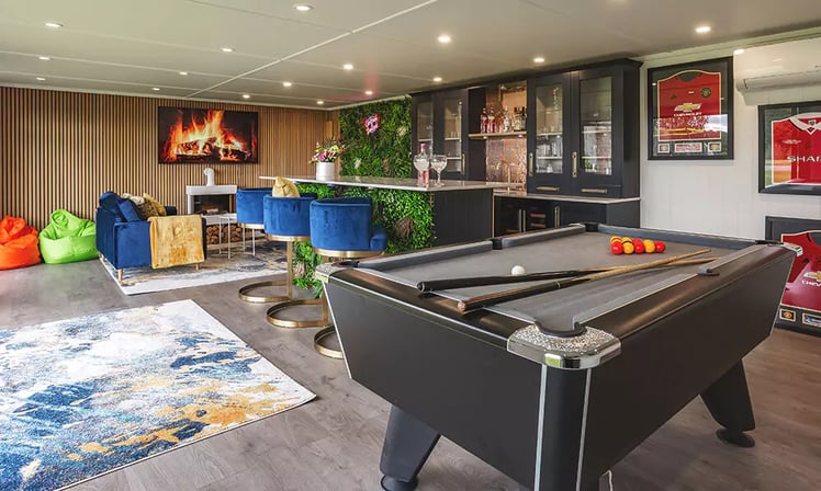 man cave with pool table & framed football shirts on wall