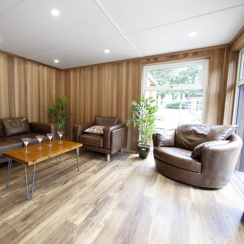 inside show site entertainments room with coffee table and cocktail glasses on it with leather sofas and armchair
