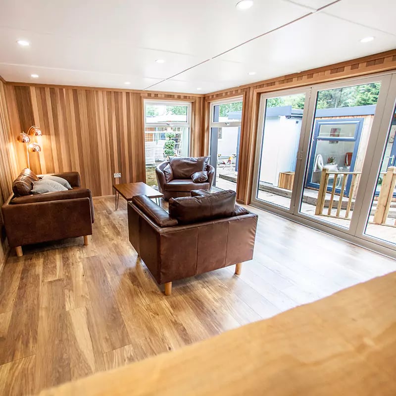 inside show site entertainments room with coffee table and cocktail glasses on it with leather sofas and armchair