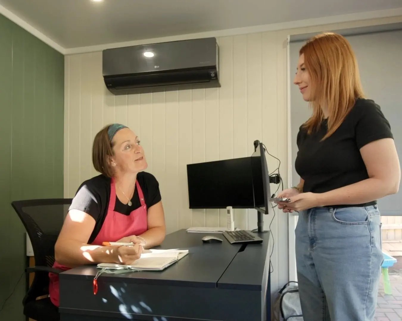 client chatting to beautician at desk in beauty room
