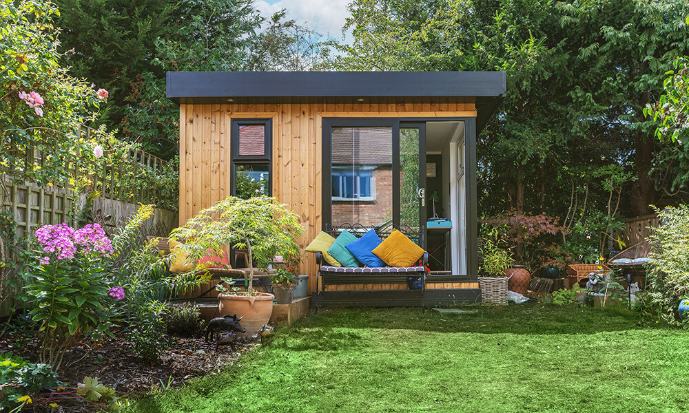 Small timber garden room in leafy summer garden