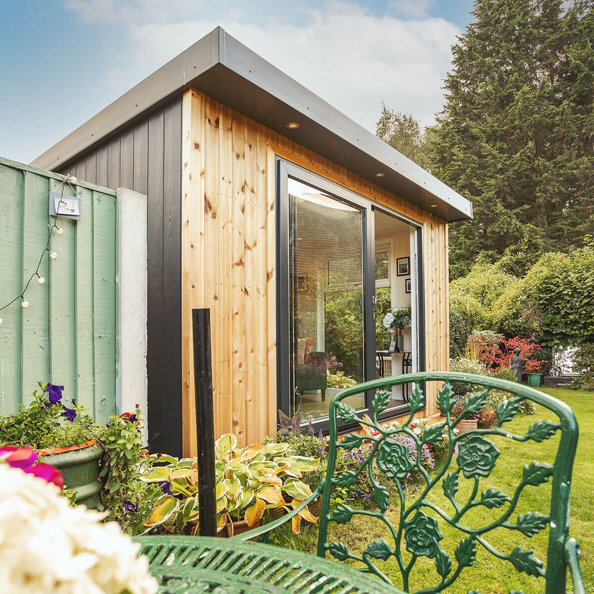 small garden summerhouse in outdoor area with potted plants and outdoor furniture with chair and tables 