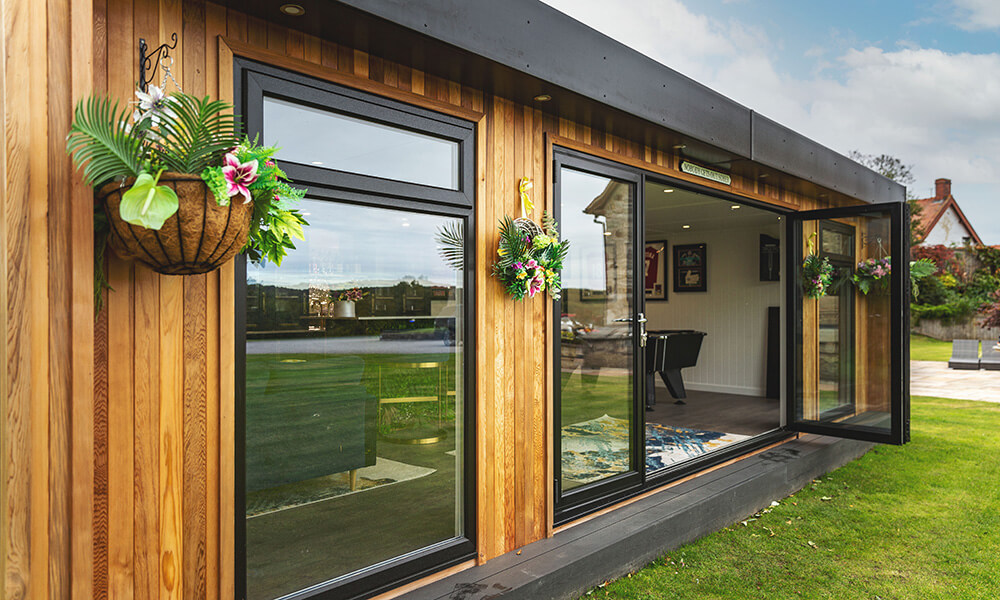 Exterior close up of a luxury insulated garden room with tropical hanging baskets