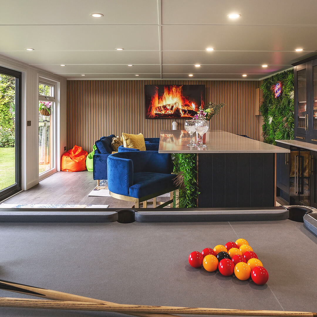 large garden bar building with pool table and countertop with glasses of gin on top of it 