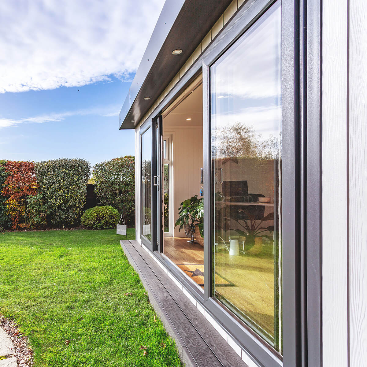 garden office space in lawn area with sliding glass doors surrounded by hedges