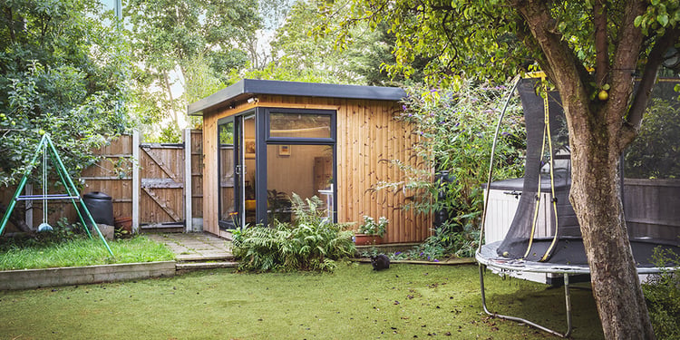 Small garden office pod in the corner of a garden in autumn