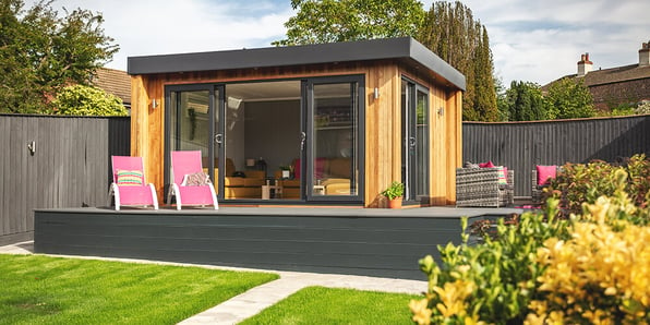 Luxury cedar summerhouse on large raised decked area with pink sun loungers outside