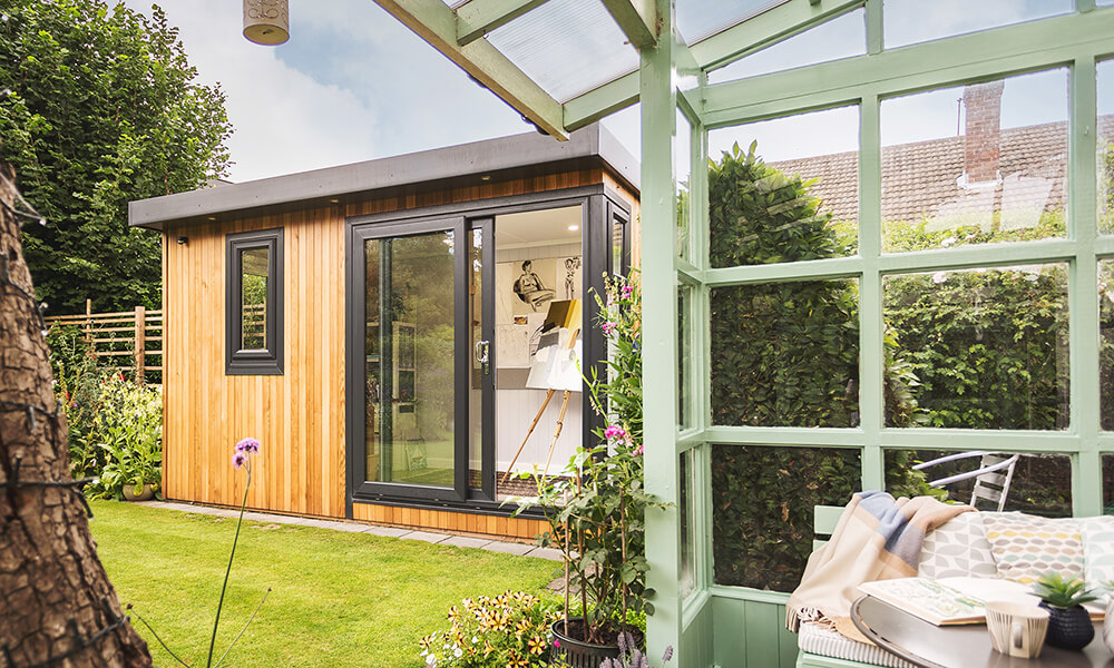 Small garden office next to sage green lean-to