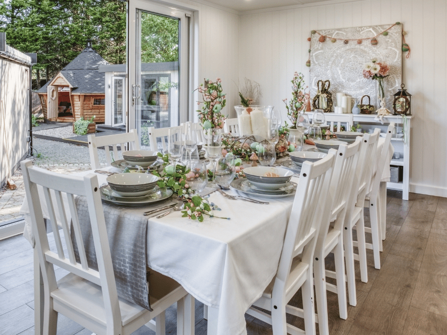 Bright garden room dining area decorated for spring and Easter with flowers and pastel table decorations.