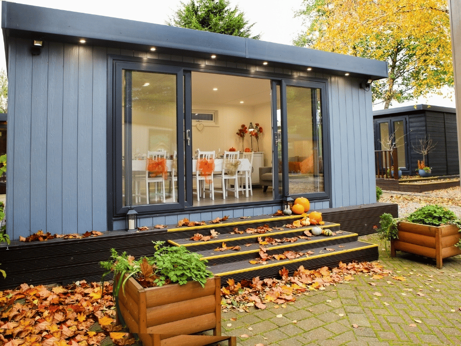 Grey Cabin Master garden room in autumn with fallen leaves and pumpkins decorating the entrance.